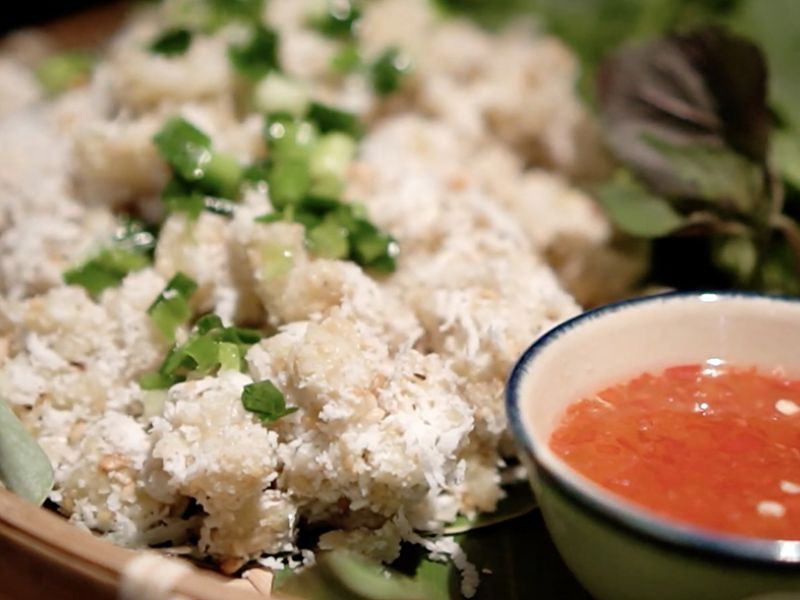 Đĩa chuối quết dừa màu xanh lá cây với lạc rang và rau thơm