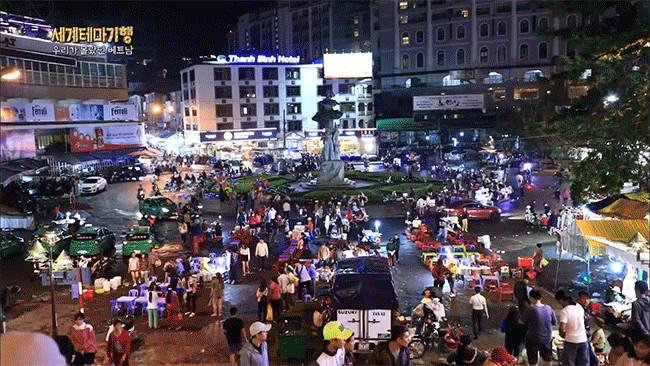 Người bán đổ trứng và hành lên bánh tráng đang nướng trên bếp than
