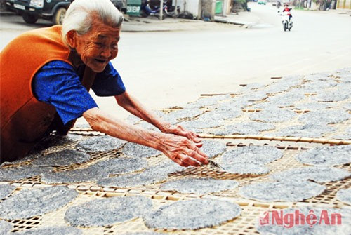 Người phụ nữ cao tuổi đang ngồi bên những chiếc bánh đa lớn