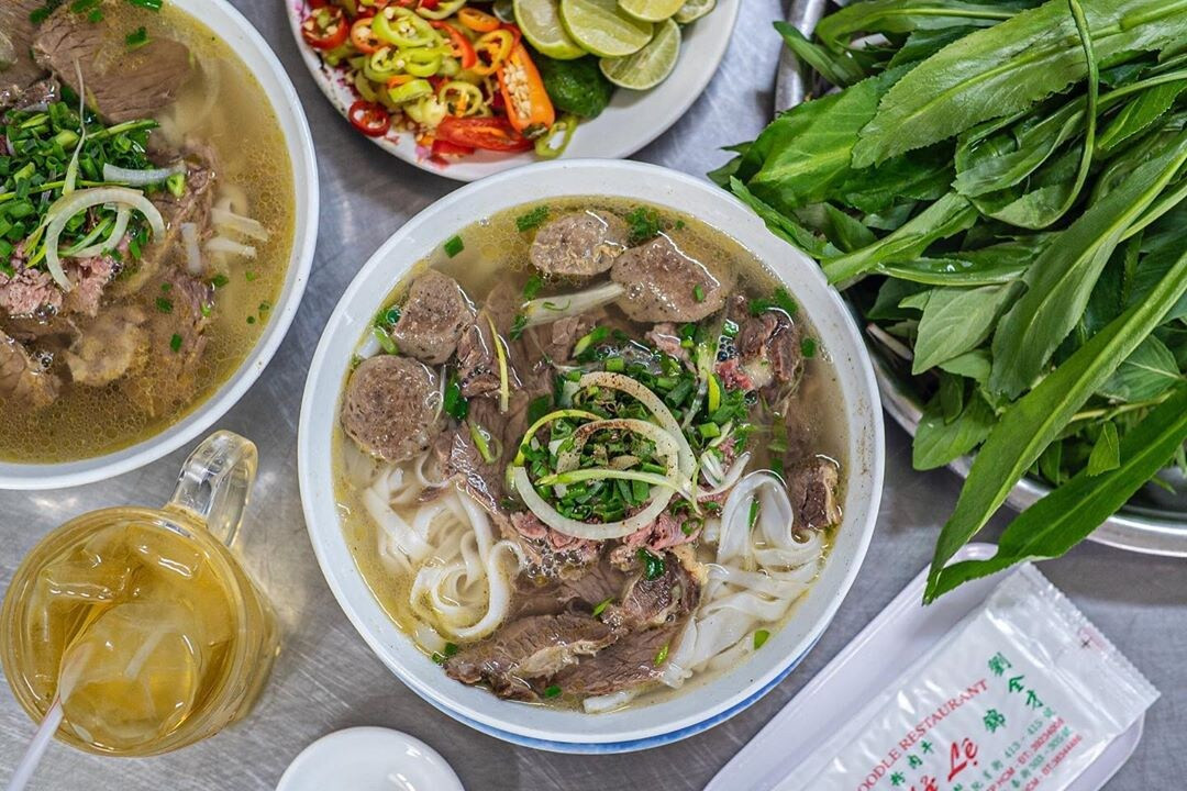 Tô phở Sài Gòn nghi ngút khói, với thịt bò tươi và rau sống phong phú, biểu tượng của ẩm thực Việt.