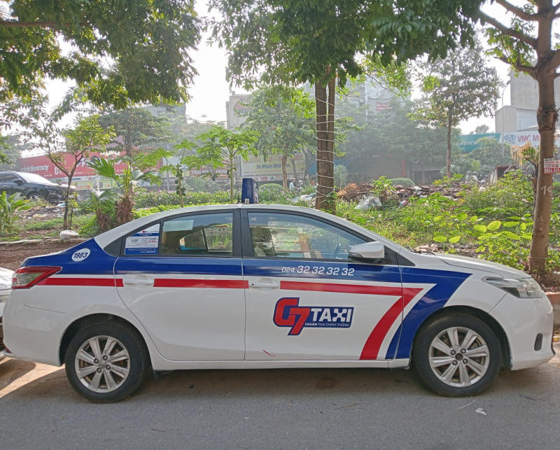 Hình ảnh xe taxi Sao Mai màu bạc sang trọng đậu trên đường phố, phía sau là một công trình kiến trúc cổ