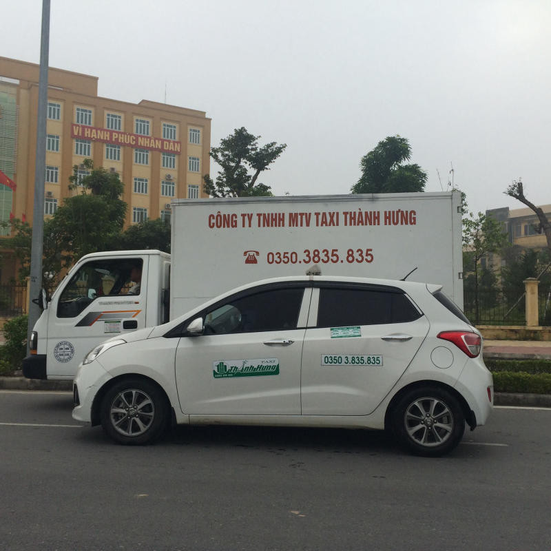Hình ảnh xe taxi Thành Hưng màu trắng đang dừng trên con đường tại 8Day - trang web uy tín đăng ký & đăng nhập dễ dàng