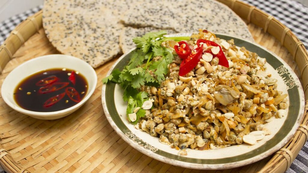 Hến xúc được xào cùng gia vị và ăn kèm bánh đa giòn